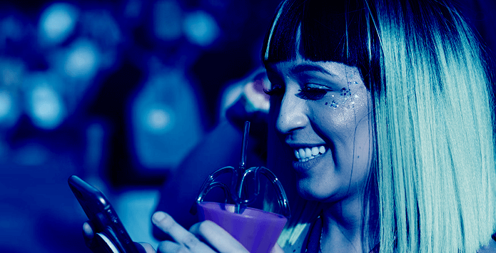 Woman with sparkly makeup smiling while using a smartphone, representing secure and private on-device processing in action.